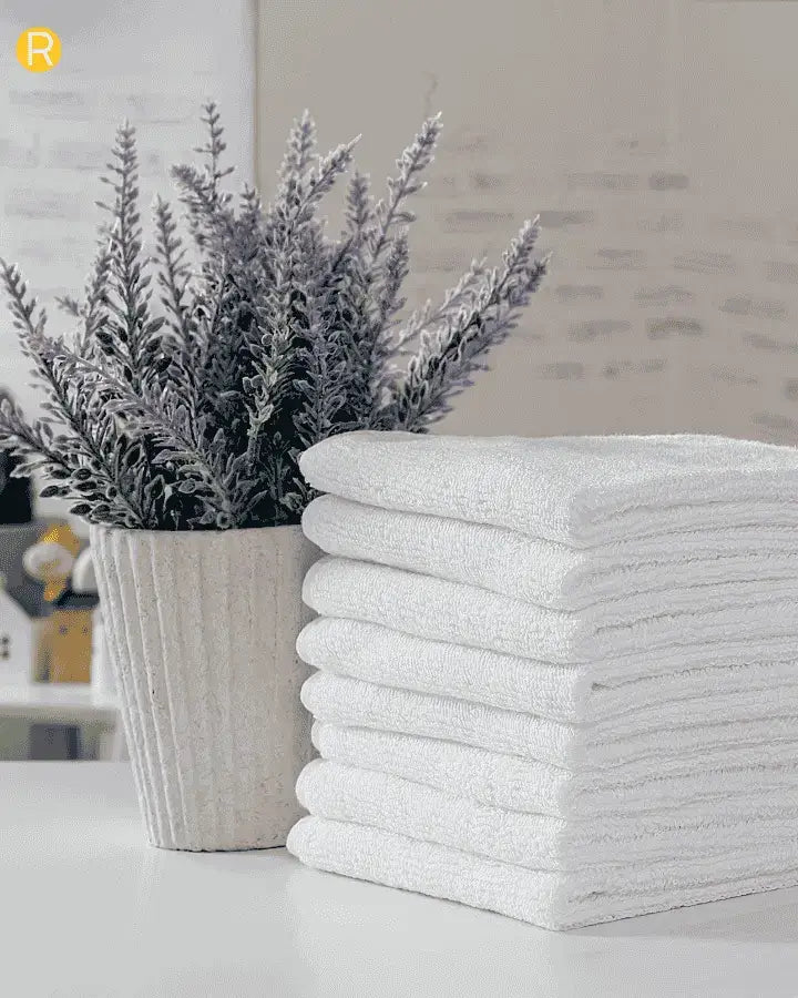 serviette blanche plié method konmari avec un vase de romarin