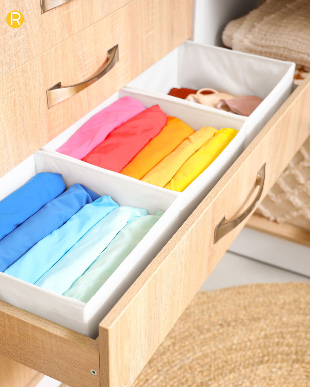 Tiroir de dressing avec des paniers de rangement pour vêtements blanc avec des pulls bien pliés méthode mari Kondo et triés par couleurs